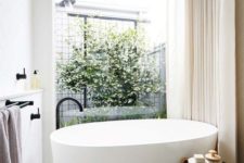16 a contemporary bathroom with an oval tub and a view to the inner courtyard with much greenery