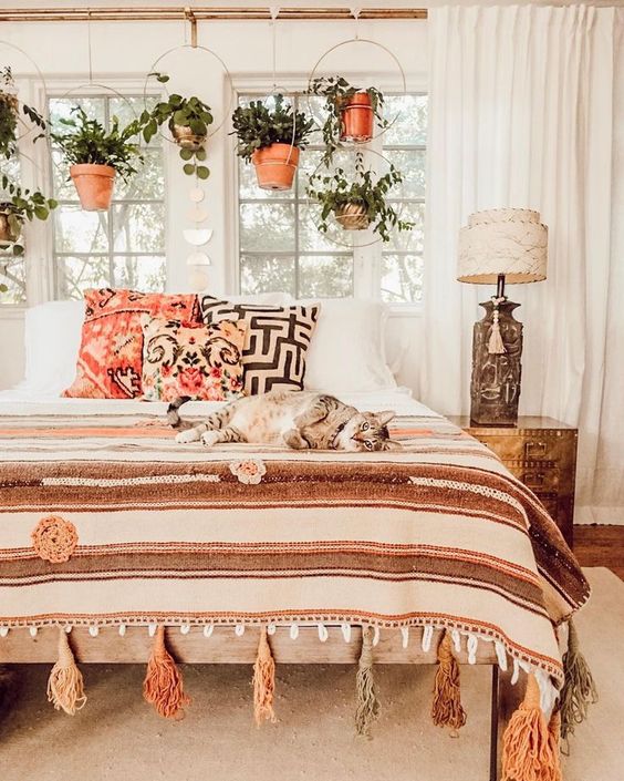 potted greenery suspended in hoops over the bed makes the space fresh