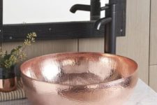 a shiny hammered copper vessel sink with a matte black faucet for a contrast is a stylish and chic idea