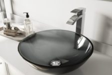 a stylish sheer black glass vessel sink looks very contemporary and a sculptural faucet increases this effect