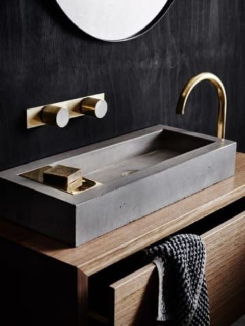 a very masculine concrete rectangular sink with some soap right on its side and some metallic touches