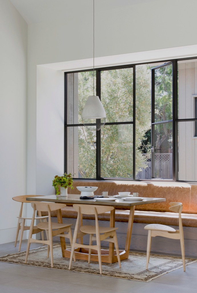a cozy breakfast nook by the window The breakfast nook is done with a leather sofa, wooden chairs, some pendant lamps and much natural light