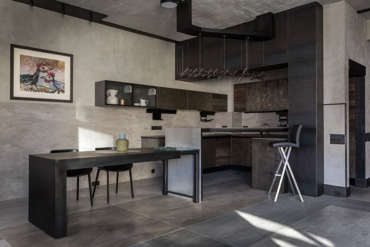 The kitchen is done in dark greys, with metal cabinets and a kitchen island that doubles as a dining space
