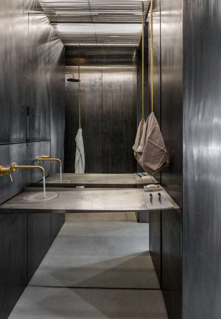 The bathroom is also clad with aged metal, too, there is gilded hardware, with a console with no separate sink and a shower space