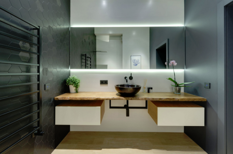 bathroom designed with hex tiles The bathroom is done with black hex tiles, sleek concrete walls, a floating vanity with storage and a lit mirror