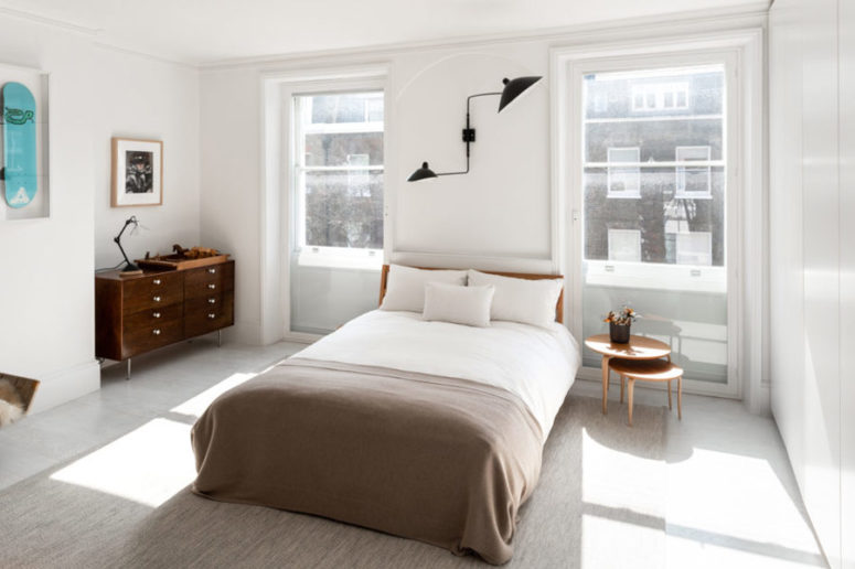 The bedroom features mid century modern style, with comfy wooden furniture, bold artworks and a black metal lamp The bedroom features mid-century modern style, with comfy wooden furniture, bold artworks and a black metal lamp