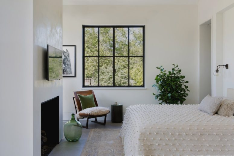 The master bedroom features a smaller window for more privacy, a fireplace, a bed and a chair with pillows and soft textiles The master bedroom features a smaller window for more privacy, a fireplace, a bed and a chair with pillows and soft textiles