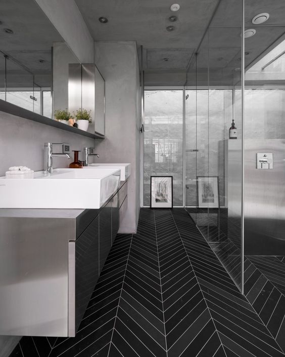 a minimalist bathroom with grey walls and a grey vnaity plus a catchy black skinny tile floor for a contrast