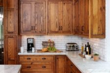 08 a rustic kitchen with warm-stained cabinets, white skinny tiles, white stoen countertops plus vintage handles