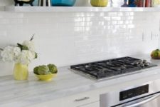 09 a stylish modern farmhouse kitchen with stone countertops and white skinny tiles on the backsplash that shines a bit