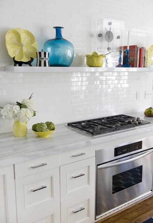 a stylish modern farmhouse kitchen with stone countertops and white skinny tiles on the backsplash that shines a bit
