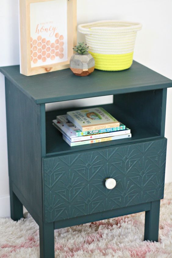 una mesita de noche IKEA Tarva está pirateada con incrustaciones de imitación, un pomo blanco y en color verde bosque