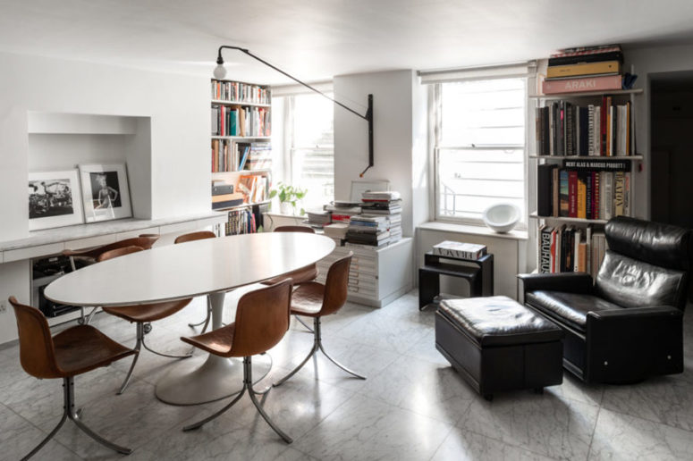 This is a shared home office with an oval table, leather chairs, a black chair and bookshelves all over