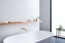 13 a chic minimalist bathroom with white skinny tiles on the wall and a white oval bathtub plus black tiles on the floor