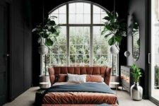 17 a trendy boho bedroom done in neutrals, black, rust and greenery with an arched window that takes the whole wall