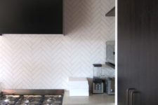 20 a dark minimalist kitchen done with concrete countertops and white skinny tiles clad in a chevron pattern for a catchy look