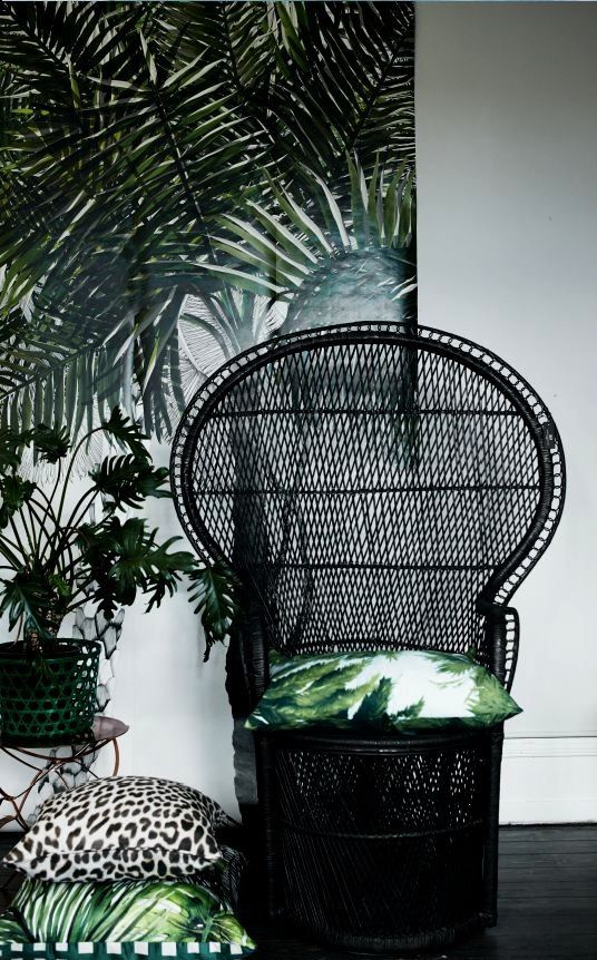 a simplified black peacock chair with bright printed pillows that add touch and freshness to it