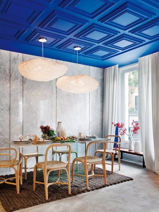 a super bright blue molded ceiling makes a bold statement in this dining room and completes the neutral space