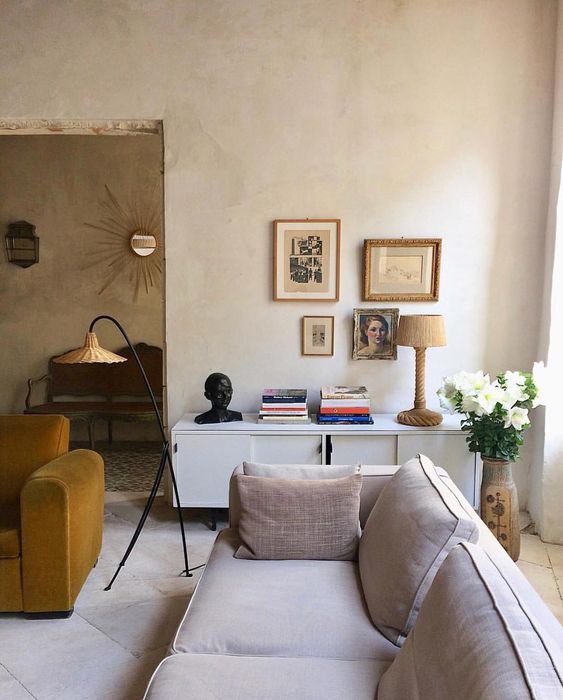 an eclectic living room with plaster walls and a metal and wicker floor lamp that adds coziness and a natural feel