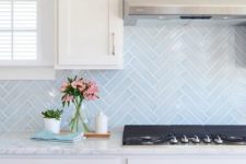 22 light blue skinny tiles done in a chevron pattern add both pattern and color to the space and make it catchier