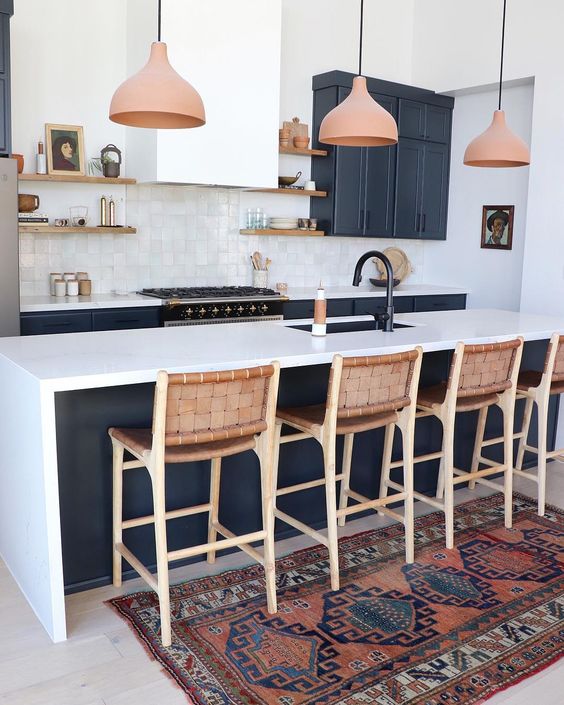 leather stools with wooden framing match the pendant lamps and refresh the monochromatic kitchen