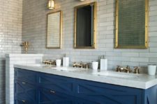 24 an art deco bathroom with marble skinny tiles, a bright blue vanity and brass touches here and there