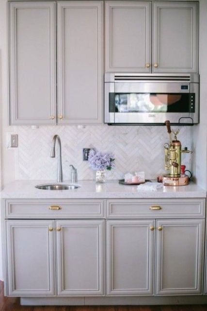 vintage grey kitchen cabinets and marble skinny tiles done in a chevron pattern for more eye-catchiness