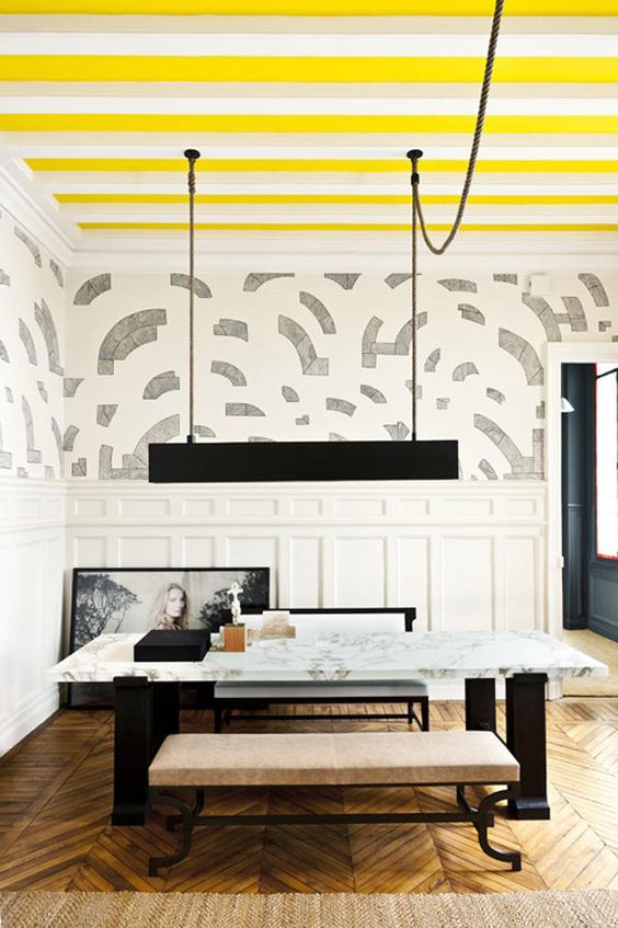 a stylish and refined dining room with a striped bright yellow and white ceiling that cheers up the monochromatic space