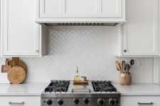 25 white skinny tiles clad in a herringbone pattern match the cabinets and add pattern interest to the kitchen