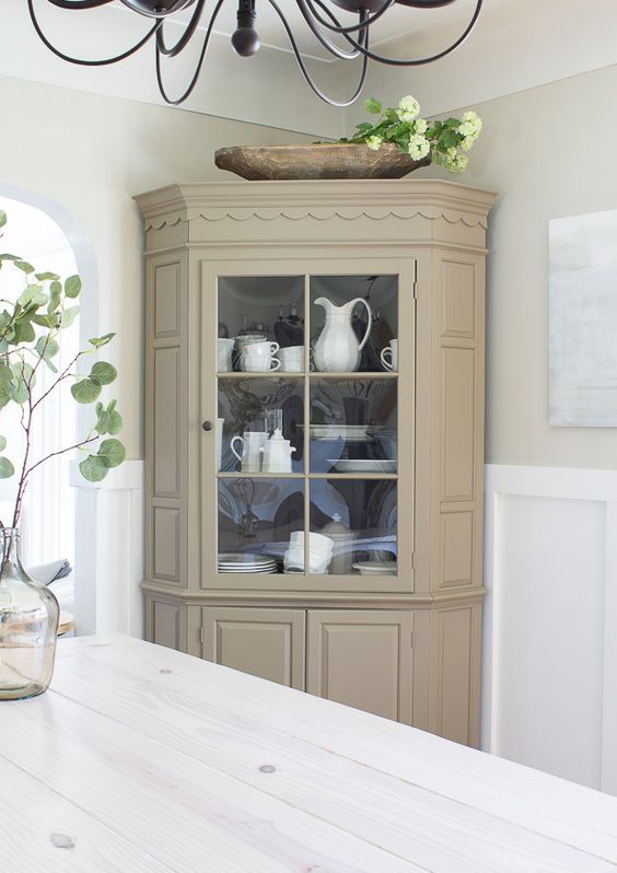 a neutral fully closed corner cabinet with some glass to display tableware in your dining space