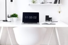 a Nordic home office in white, accented with some black touches and a black table lamp plus greenery to refresh the space
