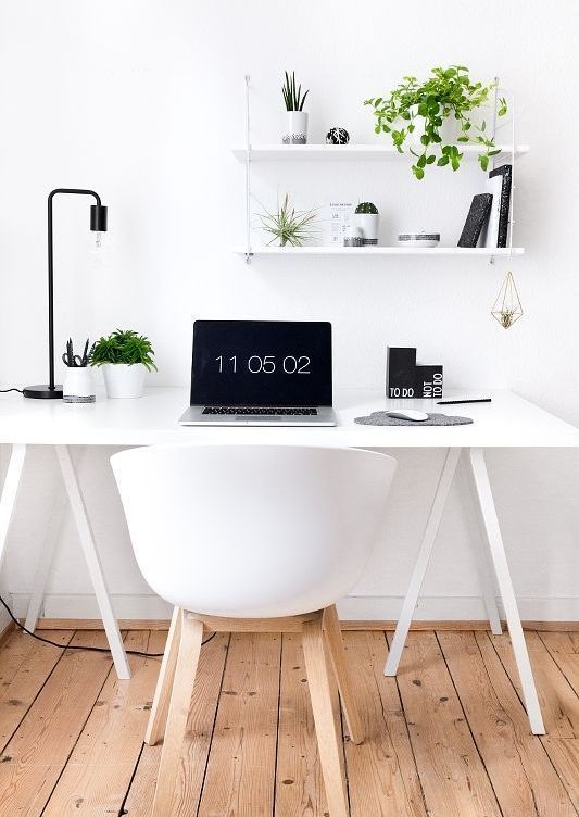 a Nordic home office in white, accented with some black touches and a black table lamp plus greenery to refresh the space