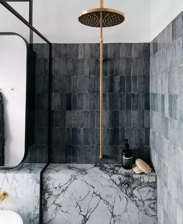 a bathroom with grey skinny Zellige tiles stacked, white marble and brass fixtures is an amazing contemporary space