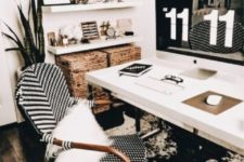 a boho black and white home office with an abstract rug, a white desk and shelves, a rattan chair and baskets for storage