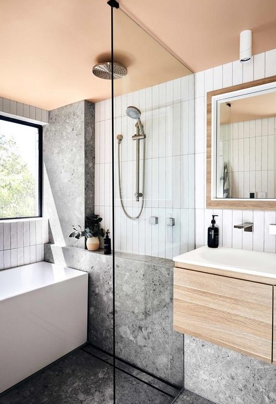 a contemporary bathroom with stacked white tiles and grey terrazzo ones, a floating vanity, a shower and a tub