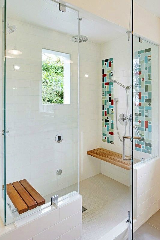 a creative shower with a window, bright tiles on the walls and small folding wooden benches for comfort