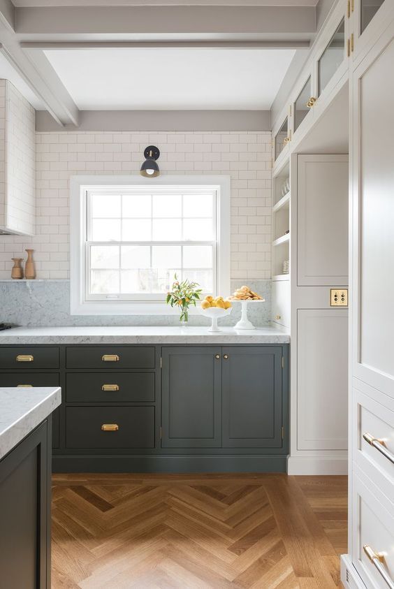a graphite grey kitchen with neutral stone countertops and neutral upper cabinets plus elegant brass hardware