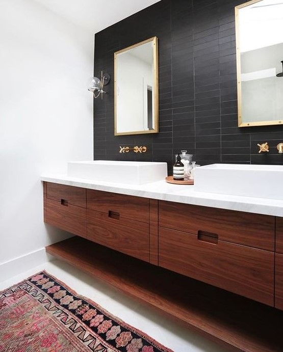 a mid-century modern bathroom with black skinny tiles on the accent wall that contrast white sinks