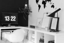 a minimalist black and white home office with a black statement wall, a map on the wall, a comfortable storage unit and a white chair