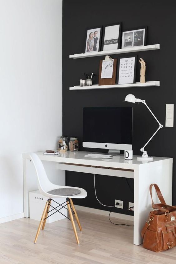 a minimalist black and white home office with a black statement wall, white furniture and some art