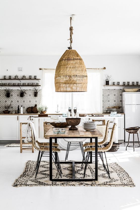 a neutral boho tropical kitchen with mosaic tiles, a wicker lamp, rattan chairs and a printed boho rug
