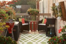 a small and bright deck with simpel woven furniture, colorful upholstery, a grill and potted greenery and flowers