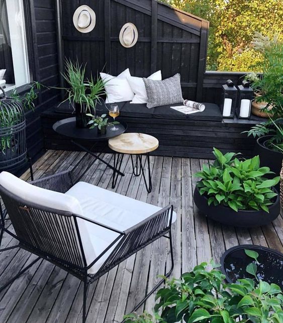 a small boho-inspired black and white deck with modern furniture, pillows, potted greenery to refresh the space
