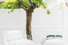 a small deck with a living tree, simple and stylish white furniture and a coffee table to serve meals