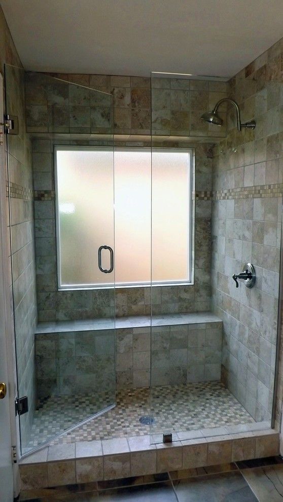 a small earthy-colored shower space with tiles of various scales and a frosted glass window plus a narrow built-in bench