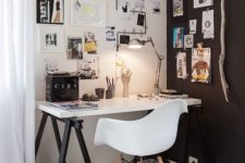 a stylish Scandinavian home office with a black and white wall, a trestle black and white desk and some artworks in black and white