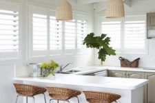 a tropial kitchen in grey and white, with wicker lampshades, wicker stools, grey cabinets and tropical plants