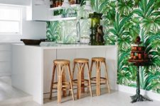 a white tropical kitchen with a tropical leaf print wall, rattan stools, a jute rug feels contemporary and boho