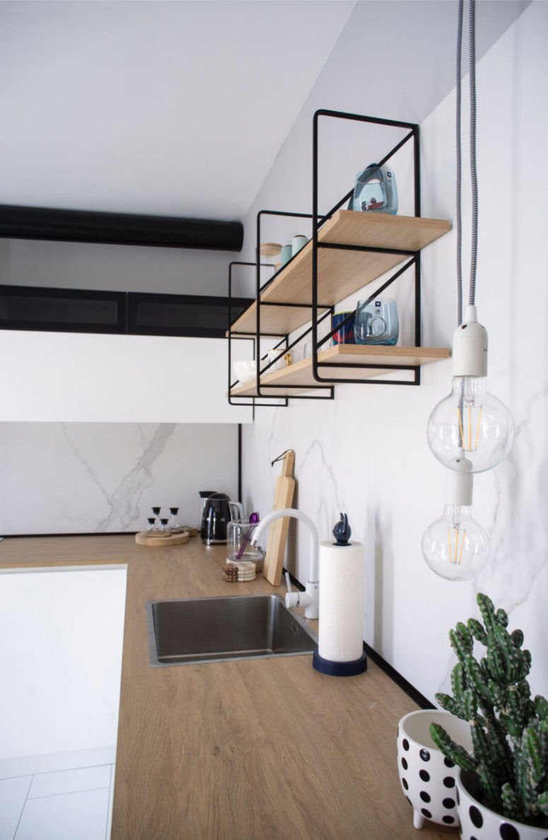 The kitchen is done with sleek white cabinets, a wooden countertop, white marble and open shelving units