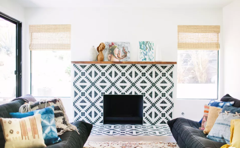 a modern fireplace clad with geometric black and white tiles that are extended to the floor for safety reasons